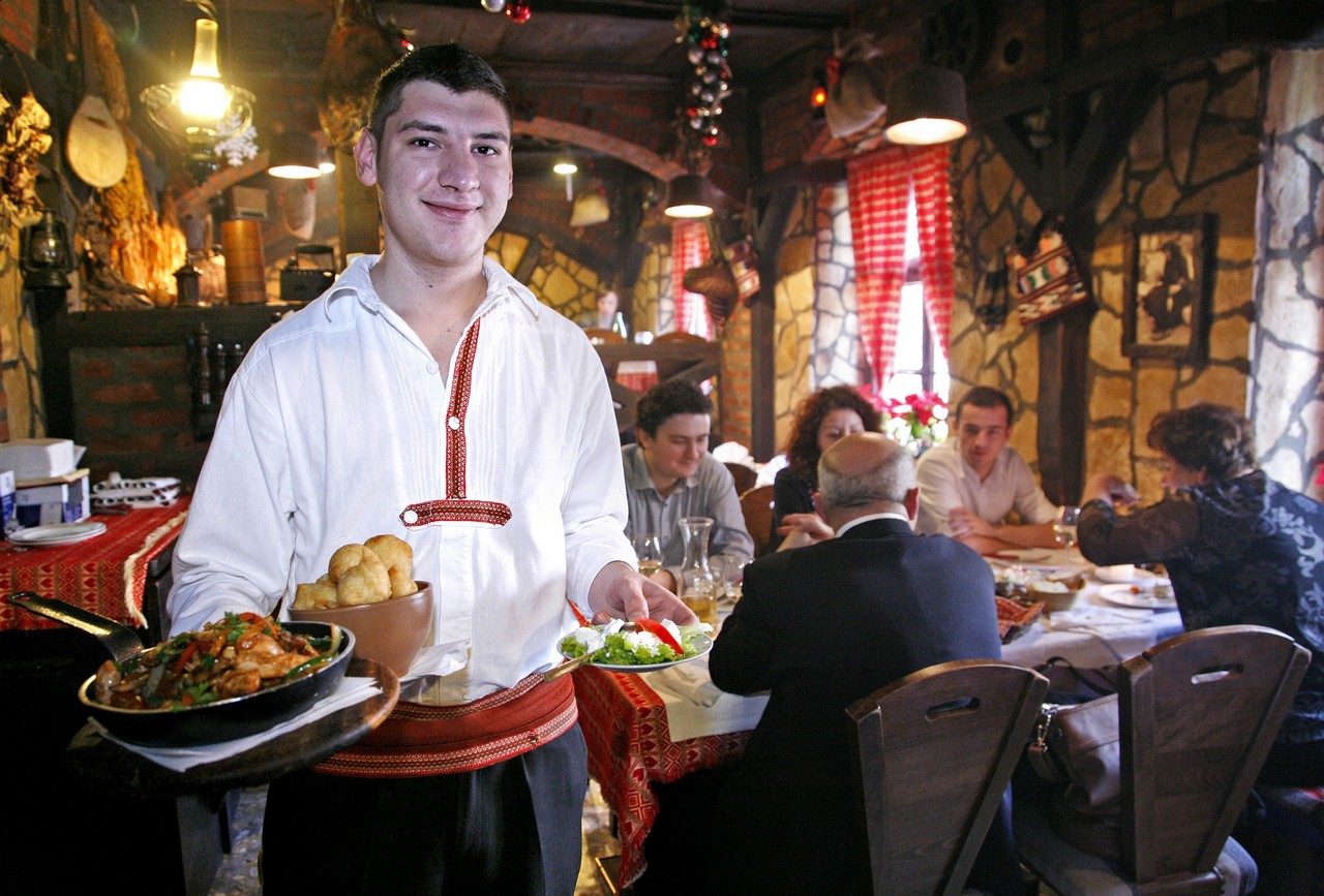 Konobar u narodnoj nošnji poslužuje jela u Konobi Didov San